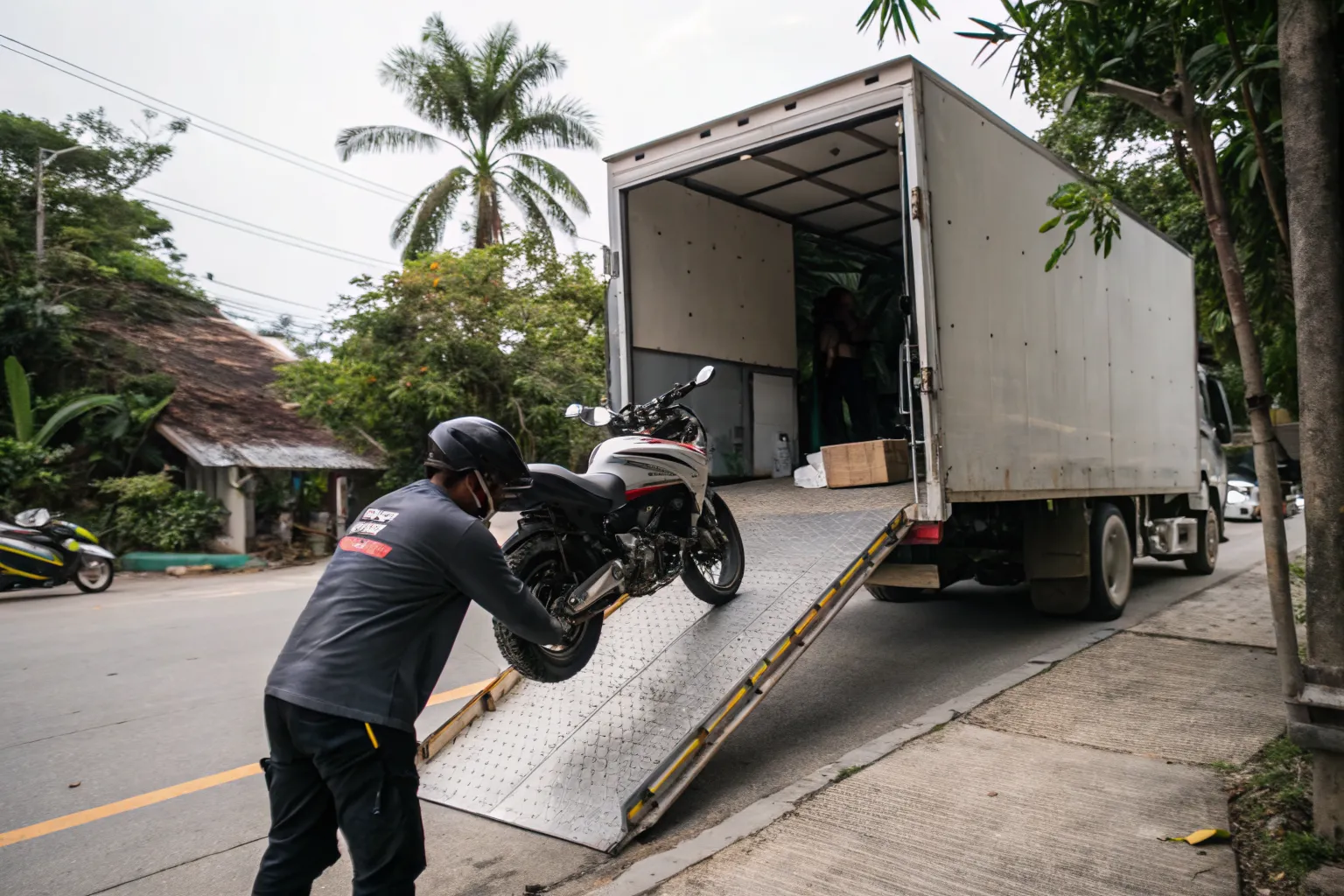 Crew rolling an adventure motorcycle up a loading ramp into a box truck