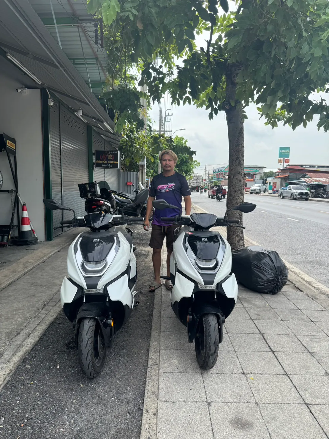 Two white maxi scooters delivered together outside a shopfront
